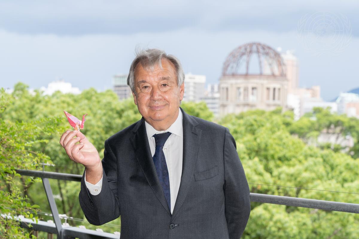 "Secretary-General António Guterres shows a paper crane origami on his hand with the Hiroshima Peace Memorial Museum dome in the background during his trip to Japan reiterating his call on world leaders to urgently eliminate stockpiles of nuclear weapons."